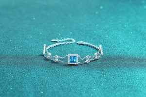 Detail of S925 silver bracelet with square blue gemstone and sparkling halo on blue glitter