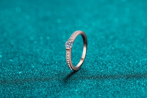 Macro view of a champagne gold moissanite ring with pave diamonds on a green surface