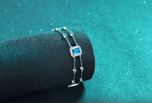 Makroaufnahme eines zweireihigen Silberarmbands mit rechteckigem blauem Saphir und Diamanthalo