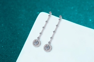 Vue macro de boucles d'oreilles pompons en argent S925 et moissanite sur socle blanc