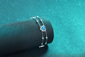 Macro view of blue heart-shaped gemstone pendant with double silver chain craftsmanship