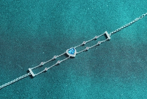 Macro shot of S925 sterling silver heart bracelet with blue moissanite and double chain