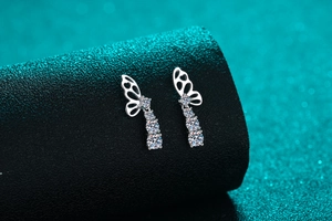 Detailed view of silver butterfly earrings with moissanite stones on black pedestal