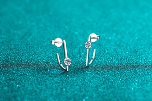 Macro shot of silver J-shaped geometric earrings with sparkling round moissanite stones