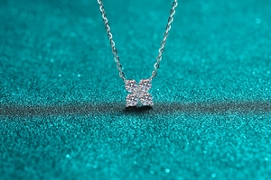 Macro detail of silver four-leaf clover pendant with moissanite crystals and fine chain