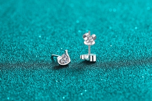 Macro shot of S925 sterling silver heart-shaped moissanite studs on blue glitter