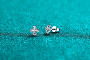Macro shot of silver S925 star stud earrings with sparkling moissanite on cyan glitter