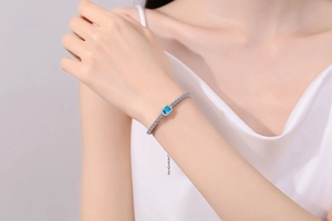 Close-up of S925 silver bracelet with square blue gemstone and pavé diamonds on wrist