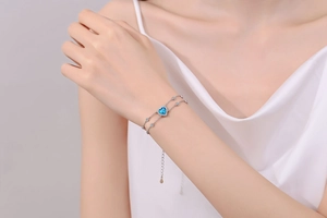 Close-up of a double-layered S925 silver bracelet featuring a blue heart-shaped moissanite