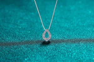 Gros plan du pendentif goutte en argent et moissanite sur fond scintillant bleu