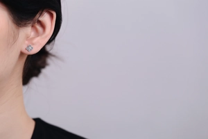 Detailed view of S925 silver four-leaf clover stud earring with blue moissanite on ear