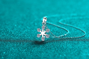 Detailed view of S925 sterling silver snowflake pendant with moissanite on blue glitter