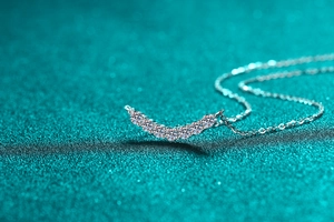 Macro shot of 925 silver necklace featuring seven moissanite stones in a smile curve