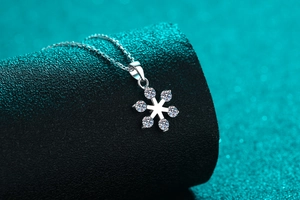 Macro shot of silver snowflake pendant necklace with sparkling stones on dark display