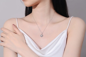 Detailed view of silver snowflake pendant necklace with blue moissanite on model