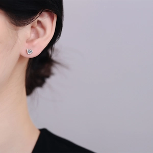 Elegant S925 sterling silver heart stud earrings with sparkling moissanite on model ear