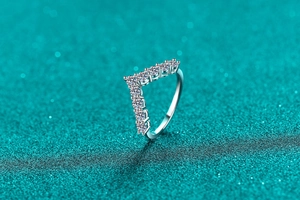 Macro detail of V-shaped moissanite ring with pave setting on dark starry background