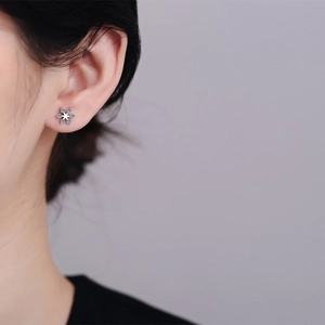 S925 sterling silver snowflake stud earrings with moissanite on model ear close-up