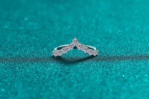 Macro shot of V-shaped sterling silver ring with sparkling moissanite stones on glitter base