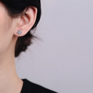 Elegant S925 sterling silver four-leaf clover stud earrings with blue moissanite on model