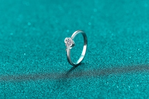 Macro shot of S925 sterling silver ring with heart-cut moissanite on sparkling green background
