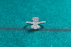 Macro shot of heart-shaped moissanite ring with side diamonds on green glitter