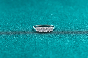 Gros plan d'une bague en argent avec cinq pierres taille brillant sur fond bleu étincelant