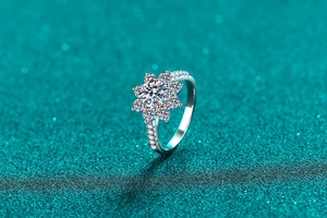 Macro shot of S925 sterling silver sunflower ring with moissanite center on blue glitter