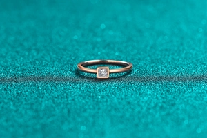 Detail of rose gold ring featuring a square-cut moissanite stone in a bezel setting