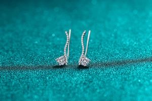 Detailed view of silver heart-shaped moissanite climber earrings with sparkling side stones
