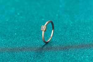 Macro shot of princess cut moissanite set in minimalist champagne gold ring band
