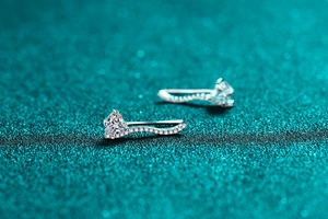 Macro shot of S925 silver heart moissanite studs with sparkling wavy pave-set stones