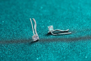Detailed view of silver curved crawler earrings featuring sparkling moissanite stones