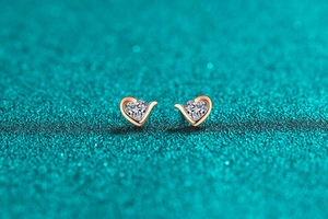 Macro shot of heart-shaped moissanite earrings in rose gold finish with wing setting