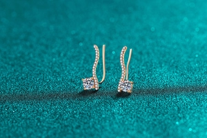 Détail macro de boucles d'oreilles courbes en or avec moissanite ronde et pavé de pierres