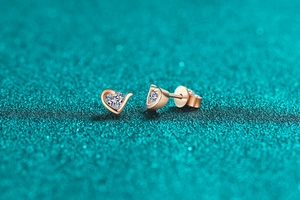 Macro detail of heart-shaped rose gold stud earrings with sparkling moissanite stones