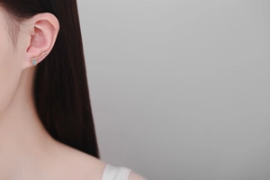 Détail de boucles d'oreilles cœur en or champagne avec pierre bleue sur un mannequin