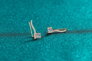 Détail macro de boucles d'oreilles en argent S925 avec moissanite et lignes ondulées or