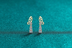Macro shot of gold butterfly stud earring with three sparkling round-cut moissanite stones