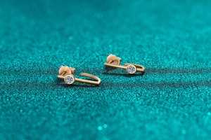 Detailed macro of rose gold irregular line stud earring with brilliant moissanite stone