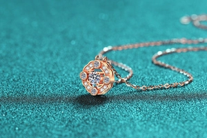 Dettaglio macro del ciondolo a fiore in oro rosa con moissanite centrale e diamanti pavé