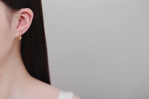 Close-up of minimalist rose gold ear studs with sparkling round moissanite on a model