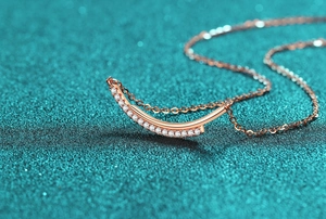 Close-up of 18K rose gold smile necklace with pave-set moissanite on blue background