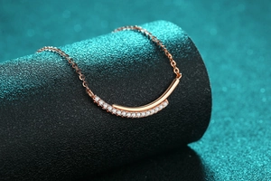 Macro shot of rose gold smile necklace with pave-set stones on a black display pedestal