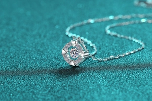 Macro detail of S925 silver moissanite heart pendant with circular cut on green background