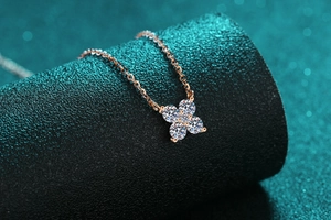 Macro view of rose gold four-petal flower pendant with sparkling round-cut moissanite gems