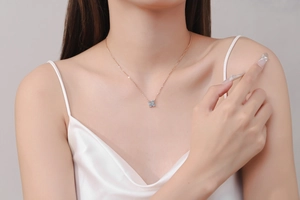 Close-up of a rose gold four-leaf clover pendant necklace with clear round-cut crystals