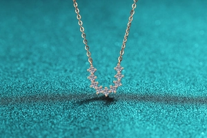 Gros plan du pendentif en forme de U en or rose avec sept pierres de moissanite serties