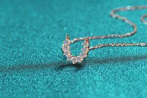 Vue macro du pendentif en or rose en forme de U avec pierres rondes étincelantes