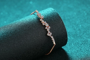 Détail macro d'un bracelet en or rose avec des breloques étoiles serties de zircons brillants